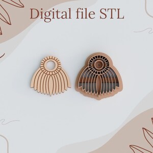 Może przedstawiać: Dwa drewniane kolczyki z geometrycznym wzorem. Kolczyki mają kształt wachlarza z kółkiem w środku. Kolczyki są pokazane na białym tle z brązowym i białym abstrakcyjnym wzorem.