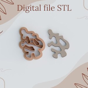 May include: Two abstract cookie cutters, one light brown and the other light grey, are shown on a white background. The text "Digital file STL" is at the top. The cutters have an organic, flowing design, suitable for baking. The background has a neutral colour scheme.