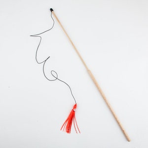 May include: A wooden fishing rod with a black tip and a red and white lure attached to a black string.