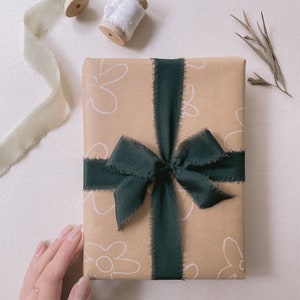 Gift wrapped in Christmas Silk Ribbons in Dark Green with sage and white silk ribbon spools above on display