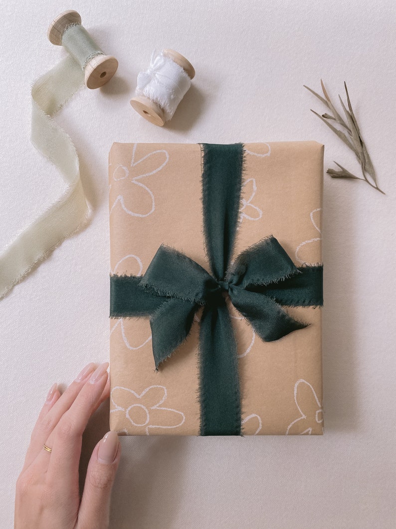 Gift wrapped in Christmas Silk Ribbons in Dark Green with sage and white silk ribbon spools above on display