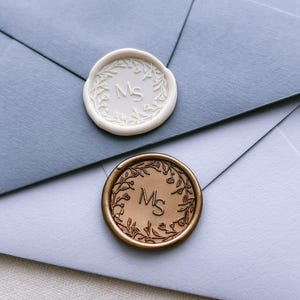 white and gold floral wreath custom monogram wax seals personalized with initials on blue envelopes
