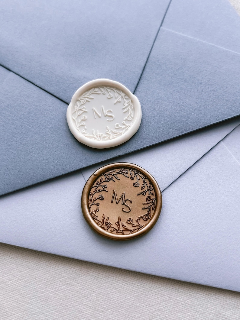 white and gold floral wreath custom monogram wax seals personalized with initials on blue envelopes