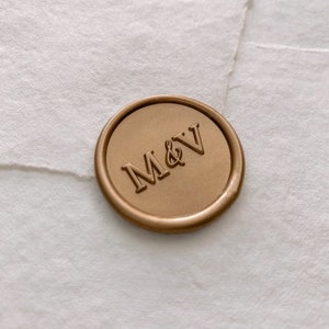 Monogram round wax seal in gold on white handmade paper envelope, side angle