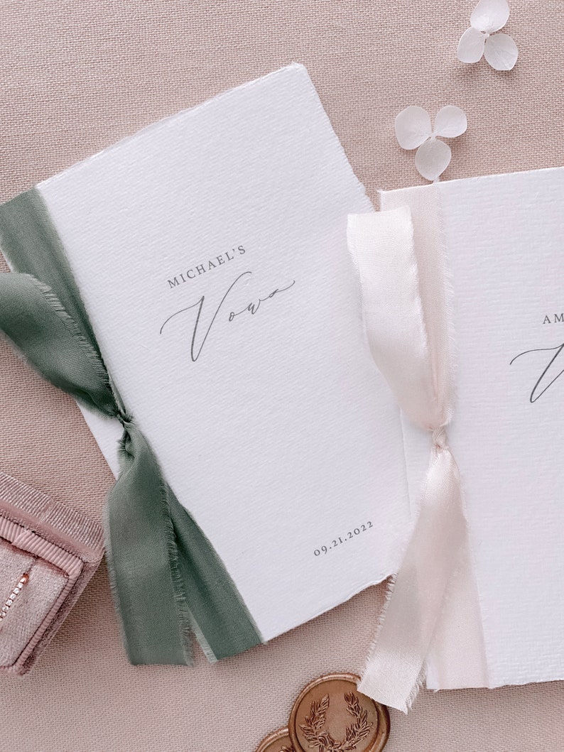 Set of 2 white handmade paper vow books printed with personalized names and date, tied in olive green and nude silk ribbons