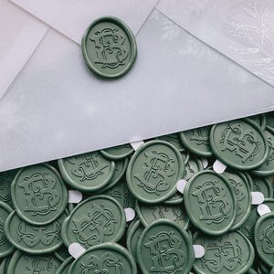 Pu&ograve; includere: Primo piano di un mucchio di sigilli di cera verde con una lettera "B" monogrammata al centro di ogni sigillo.