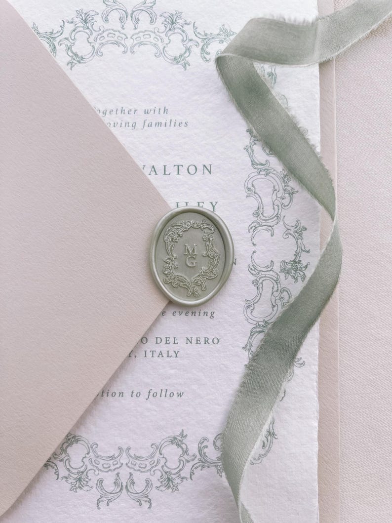 Light metallic green vintage crest monogram oval wax seal on a wedding invitation card and beige envelope