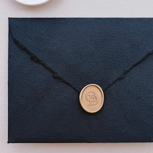 Gold simple design custom monogram logo wax seal on a black envelope