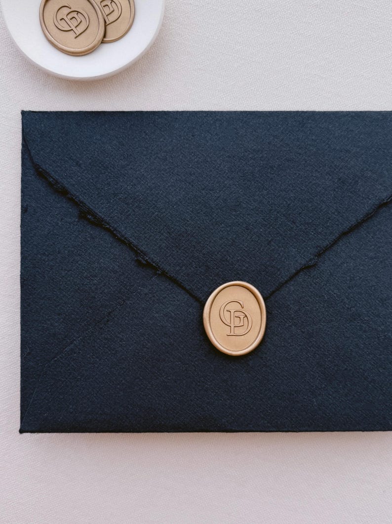 Gold simple design custom monogram logo wax seal on a black envelope