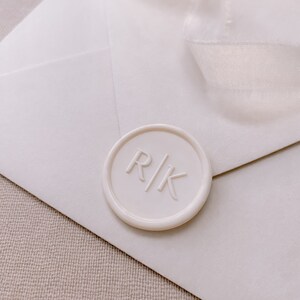 Modern font monogram round wax seal in off-white on white envelope