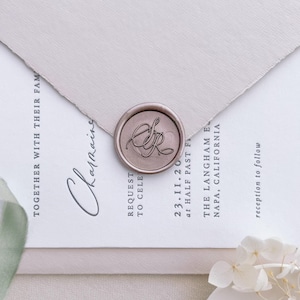 Light bronze personalized monogram wax seal on a light pink wedding invitation envelope