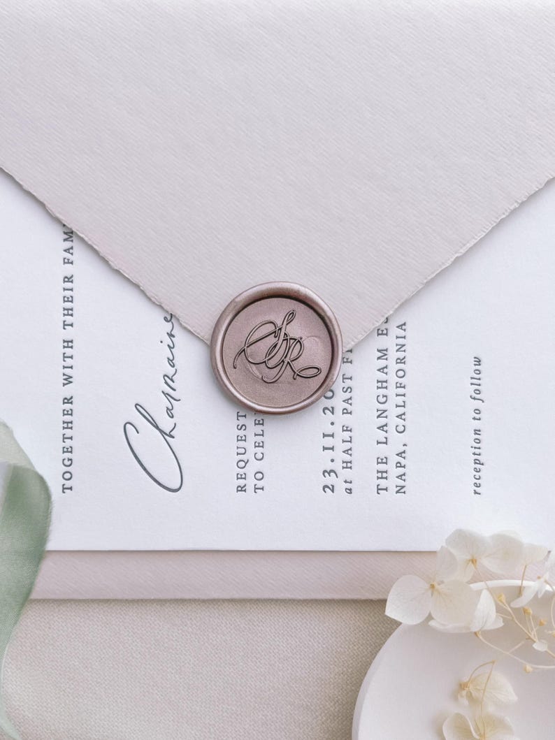 Light bronze personalized monogram wax seal on a light pink wedding invitation envelope