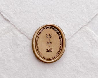 Può includere: Un sigillo di cera color oro con i numeri 15, 10 e 26 in rilievo. Il sigillo è di forma ovale con un bordo decorativo ed è posto su uno sfondo di carta bianca. I numeri sono centrati all'interno del sigillo.