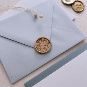 light blue envelope with gold floral wax seal