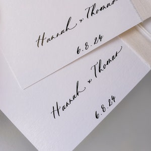Inner cover of 2 white vow books personalized with the couple's names in calligraphy script and wedding date in black ink