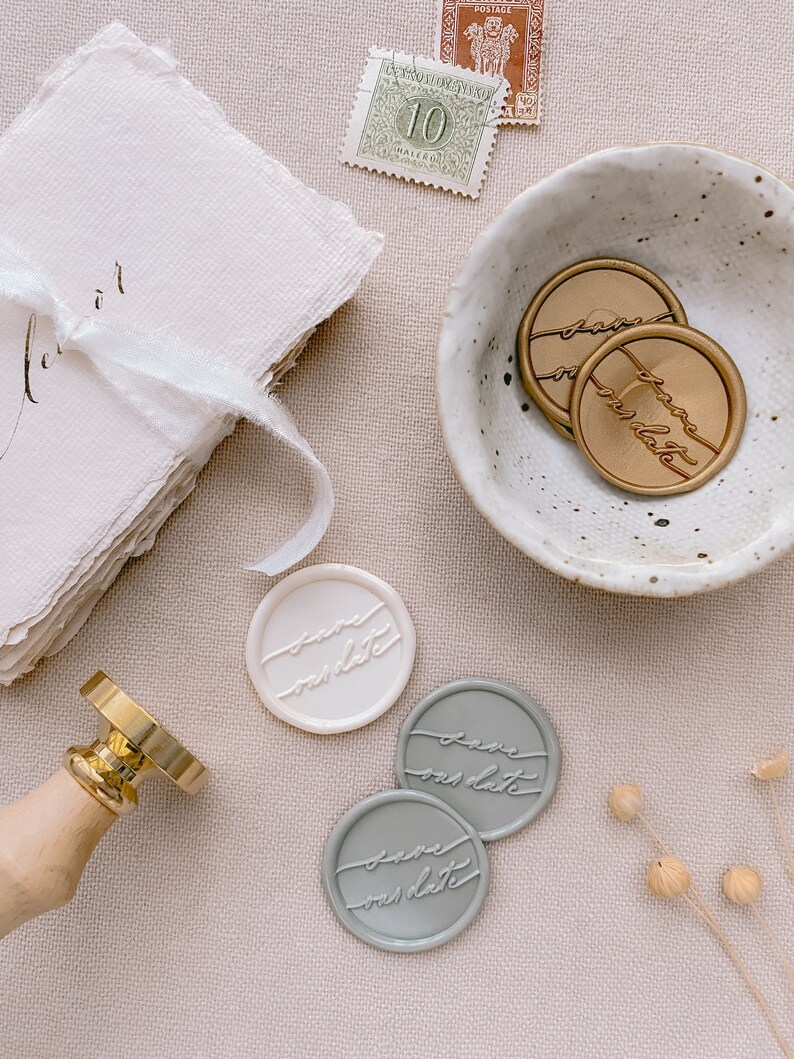 Calligraphy script Save our Date wax seals in gold, off-white and sage, styled with dried flower, ceramic dish and place cards