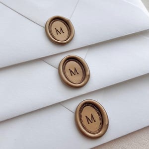 custom initial oval gold wax seals on white envelopes