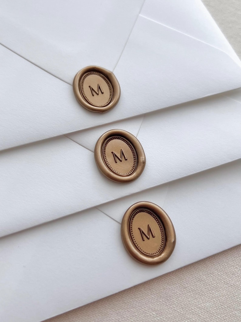 custom initial oval gold wax seals on white envelopes