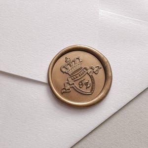 Custom crest symbol gold wax seal on a white envelope