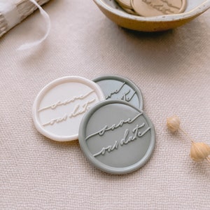 Calligraphy script Save our Date wax seals in gold, off-white and sage, styled with dried flower and a small ceramic dish