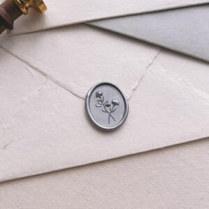 silver floral oval wax seal with 3D engraving details on white envelope