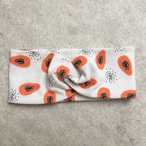May include: White headband with a papaya print. The headband is twisted and has a knot in the center.