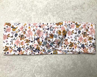 May include: A white headband with a floral pattern in shades of pink, brown, and gray. The headband is knotted in the center.