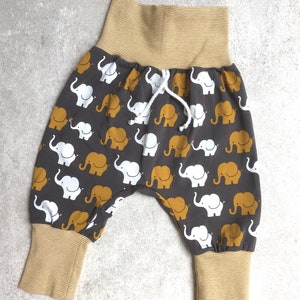 K&ouml;nnte beinhalten: Graue Babyhose mit einem wei&szlig;en und gelben Elefantenmuster. Die Hose hat einen gelben elastischen Bund und B&uuml;ndchen.