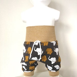 K&ouml;nnte beinhalten: Graue Babyhose mit einem wei&szlig;en und senfgelben Elefantenmuster. Die Hose hat einen senfgelben elastischen Bund und B&uuml;ndchen.