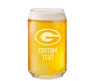 May include: A clear glass can with a frosted finish, filled with a golden yellow liquid. The can has a green and yellow logo with the letter "G" inside a circle, and the text "CUSTOM TEXT" below it.