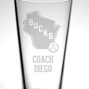 May include: A clear glass beer stein with a white outline of the state of Wisconsin and the word "BUCKS" inside the outline. A basketball is below the outline. The text "COACH DIEGO" is below the basketball.
