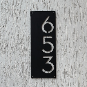 May include: Black metal house number plaque with the numbers 653 cut out in white.