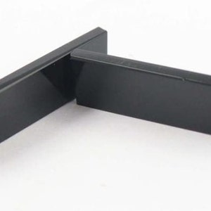 Puede incluir: Dos soportes de estante rectangulares de metal negro. Los soportes están hechos de metal liso y brillante y tienen un diseño simple y moderno.