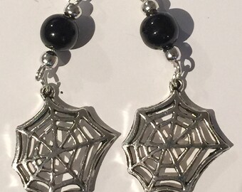 May include: A pair of dangle earrings featuring silver-toned metal spider web charms suspended from silver-toned hooks. Each earring includes a single round, polished black bead positioned above the web charm, accented by small silver-toned spacer beads.