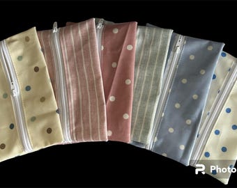 Puede incluir: Seis estuches con cremallera con diferentes patrones. Los estuches están hechos de tela y tienen una cremallera blanca. Los patrones incluyen lunares, rayas y un diseño floral.