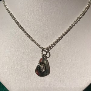 May include: A silver chain necklace with a silver charm pendant shaped like a cowboy hat.