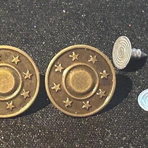 May include: Two gold-toned metal buttons with a star design and a centre circle. Two silver-toned metal button fasteners.
