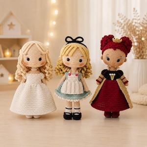 May include: Three handmade crochet dolls standing side by side. The left doll has blonde curly hair and a white dress. The center doll has blonde hair with a black bow and a blue dress with a white apron. The right doll has red hair and a red dress.