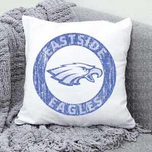 K&ouml;nnte beinhalten: Ein wei&szlig;es Kissen mit einem blauen Kreisdesign, auf dem "Eastside Eagles" steht und ein blauer Adler im Kreis abgebildet ist.