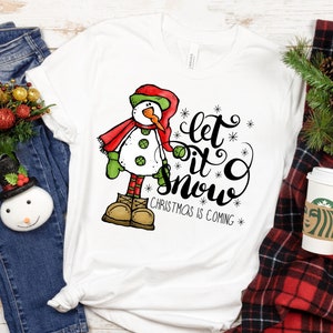 May include: White t-shirt with a cartoon snowman and the text "Let it snow Christmas is coming".