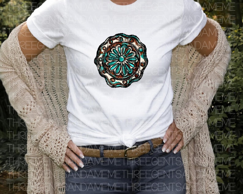 K&ouml;nnte beinhalten: Ein wei&szlig;es T-Shirt mit einem t&uuml;rkisfarbenen und braunen Mandala-Design. Das Mandala hat ein florales Muster mit einer zentralen Blume.