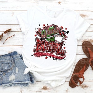 May include: White t-shirt with a red and green graphic design that says "Wheeler Baseball" with a baseball and bats. The graphic has a red glitter effect.