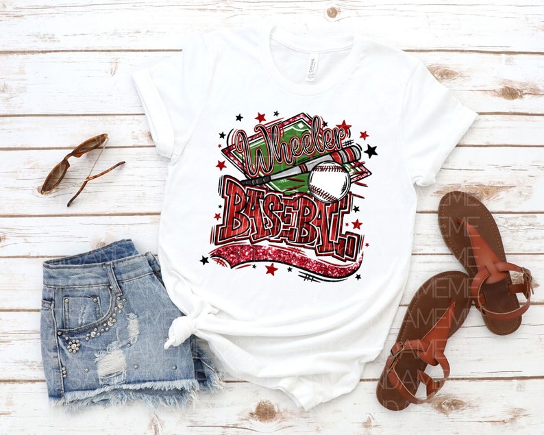 May include: White t-shirt with a red and green graphic design that says "Wheeler Baseball" with a baseball and bats. The graphic has a red glitter effect.