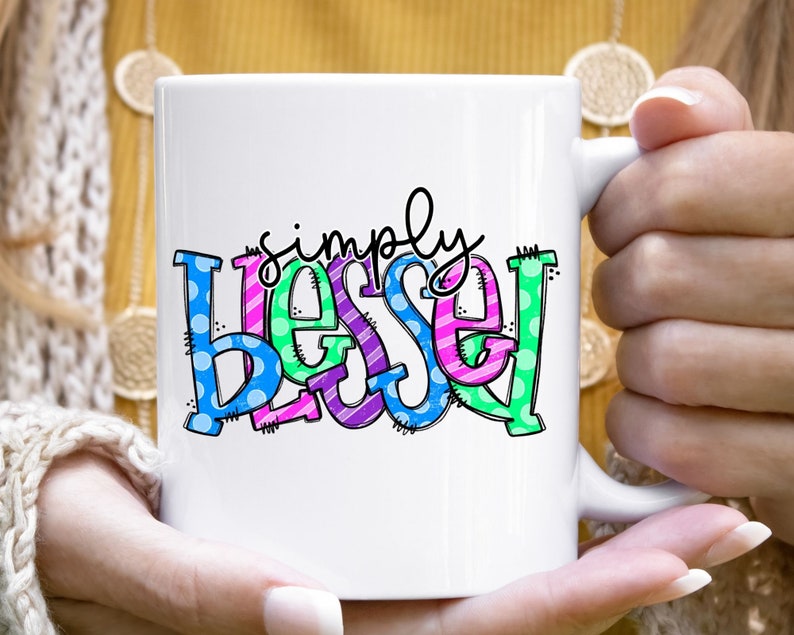 May include: White ceramic mug with a colorful design that says "simply blessed".