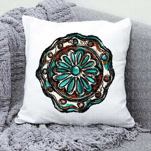 K&ouml;nnte beinhalten: Ein wei&szlig;es Kissen mit einem t&uuml;rkisfarbenen und braunen Mandala-Design. Das Mandala hat ein blumenartiges Muster mit einem t&uuml;rkisfarbenen Zentrum.