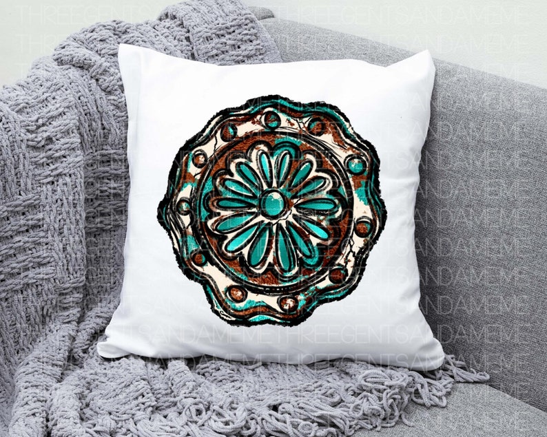 K&ouml;nnte beinhalten: Ein wei&szlig;es Kissen mit einem t&uuml;rkisfarbenen und braunen Mandala-Design. Das Mandala hat ein blumenartiges Muster mit einem t&uuml;rkisfarbenen Zentrum.