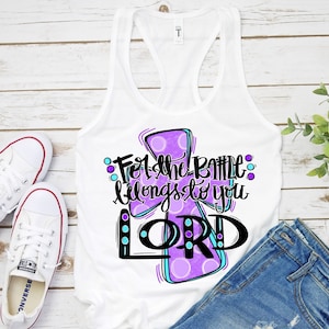 May include: White tank top with a purple and blue cross design. The text "For the battle belongs to you LORD" is written on the cross.