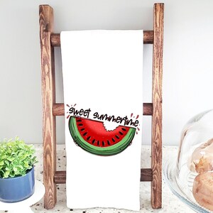 May include: White kitchen towel with a red and green watermelon slice graphic and the text "sweet summertime". The towel is hanging on a wooden ladder.