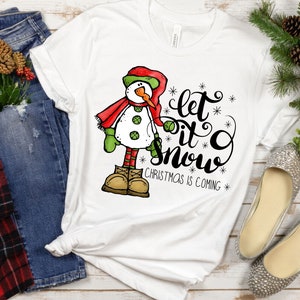 May include: White t-shirt with a snowman graphic and the text "Let it snow, Christmas is coming".