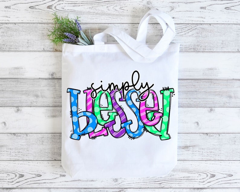 May include: White canvas tote bag with the words "simply blessed" in colorful, patterned letters. The letters are in shades of blue, green, pink, and purple.